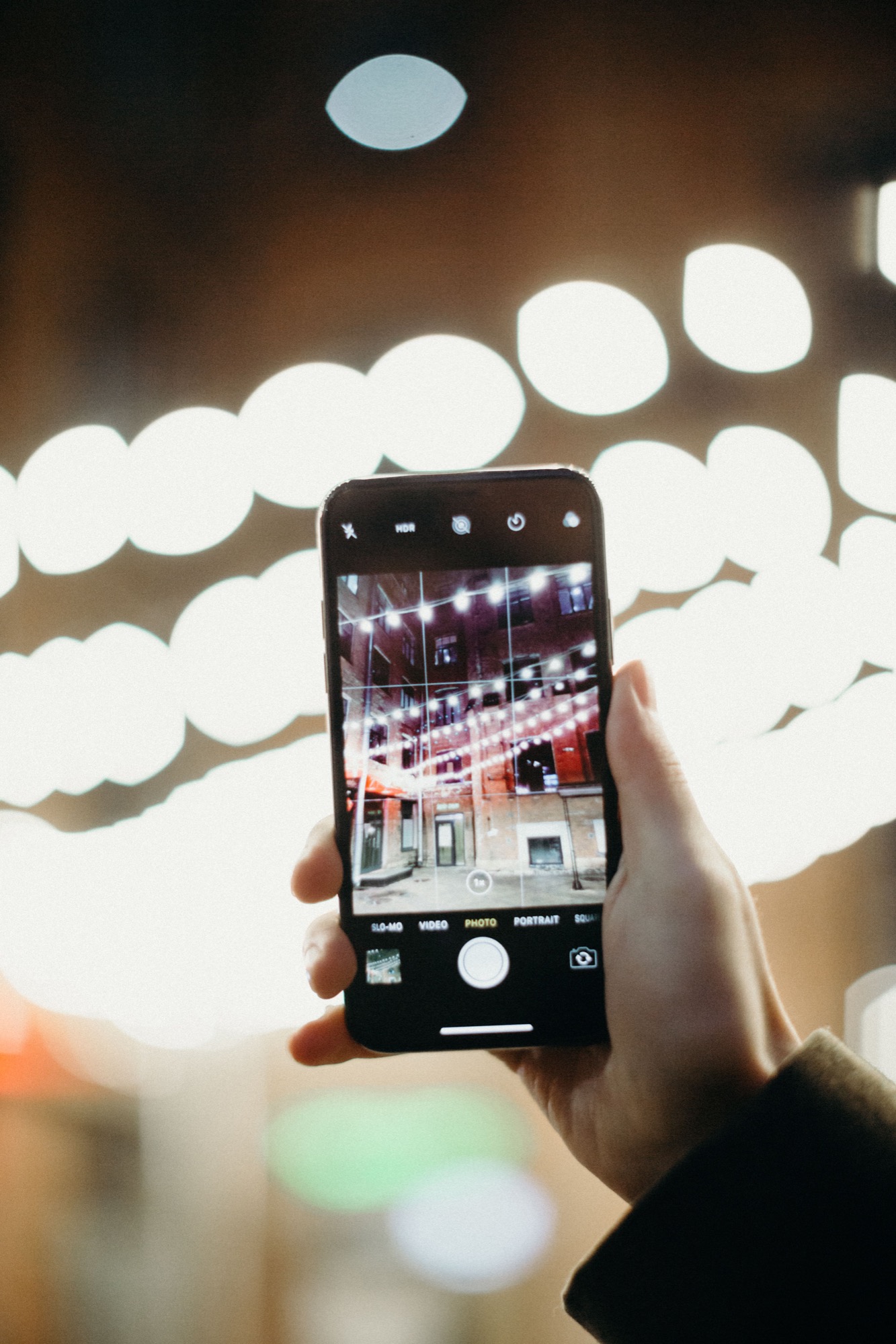 Smartphone mit Stadtlichtern als Muc Now App-Hero